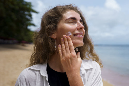 Woman applying sunscreen to her face on a sunny beach