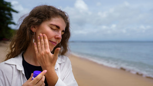 Woman applying sun protection lotion to her cheek outdoors
